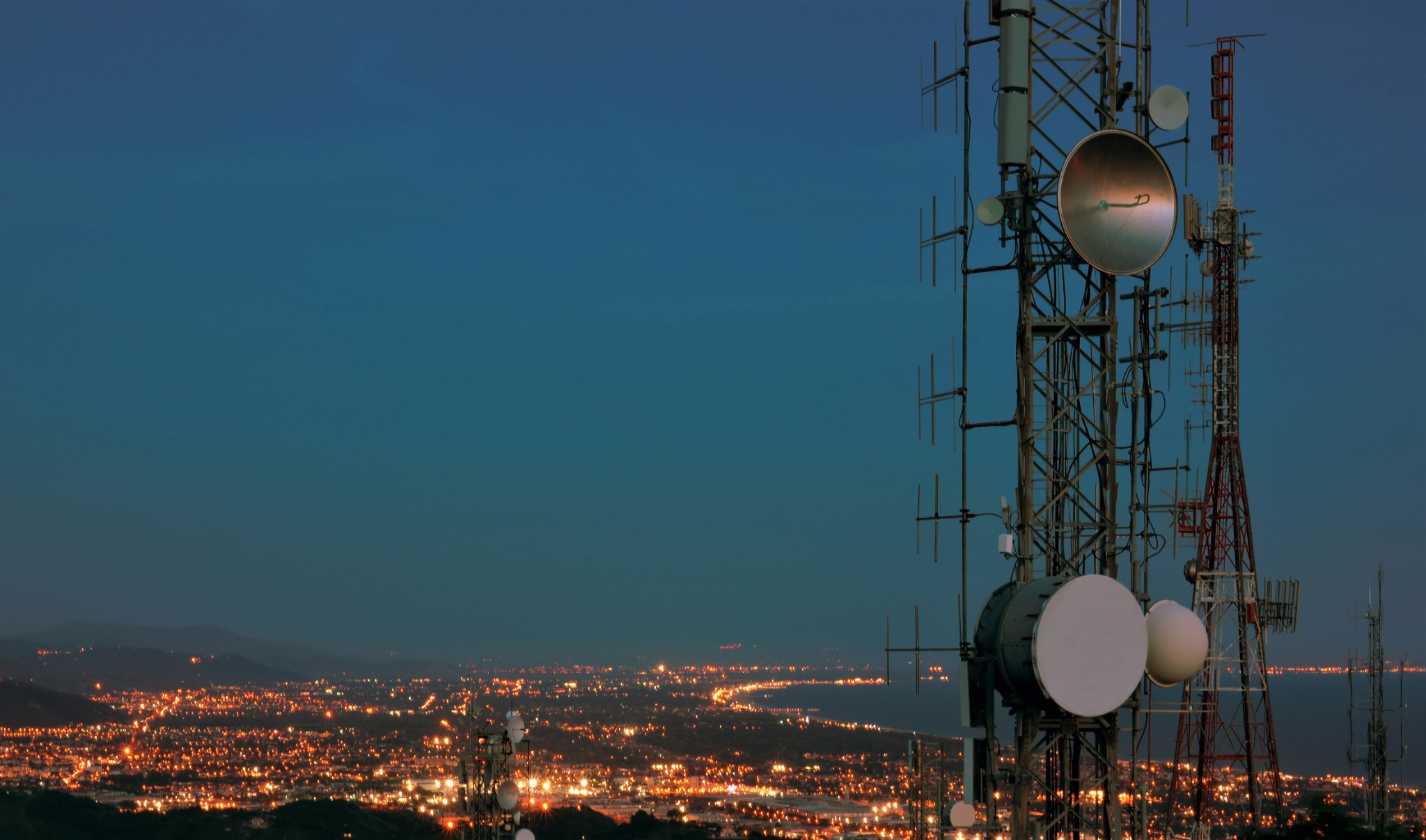 Telecommunications towers above a city at dusk