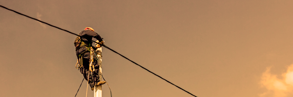 Telecommunications field technician working on a utility pole